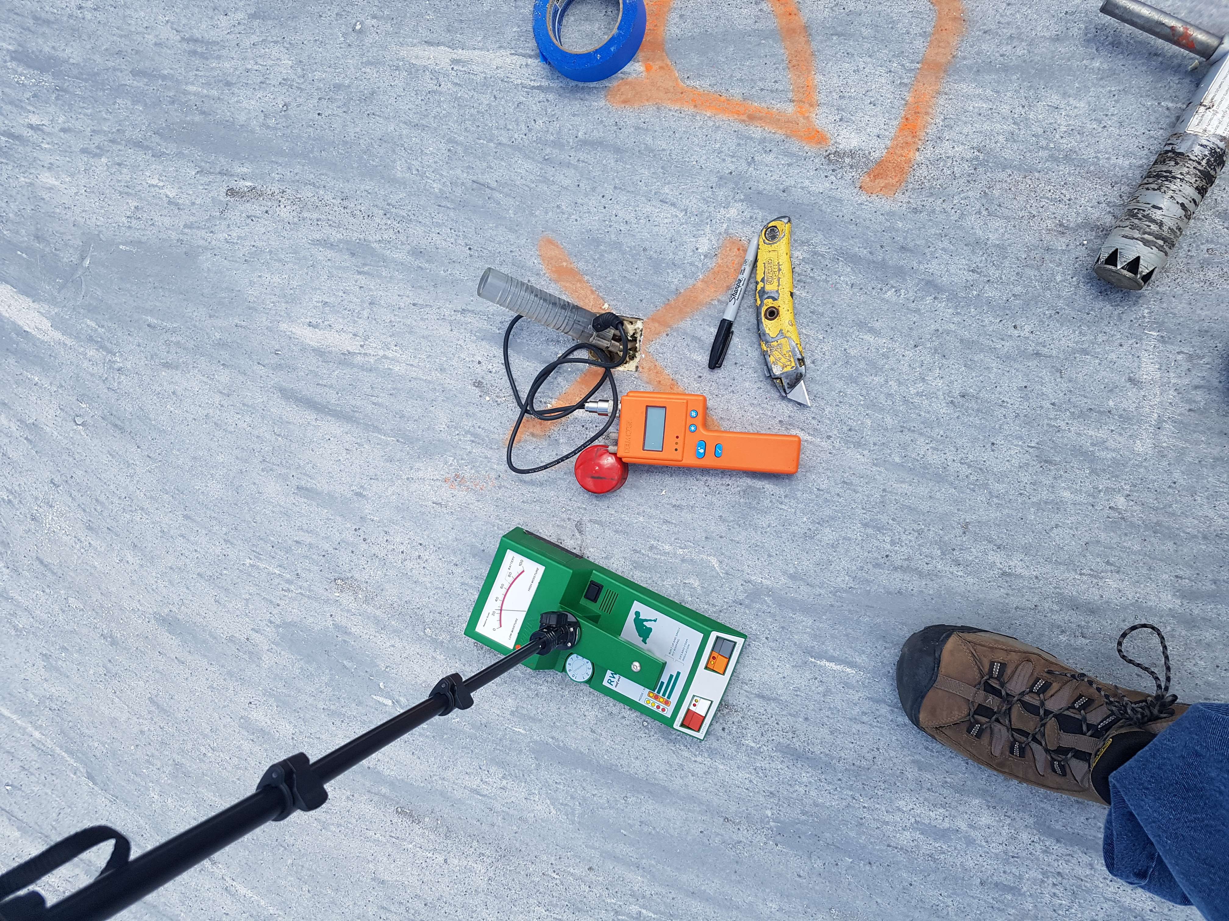 Roof moisture verification tools including nuclear moisture meter and core cutter on flat roof